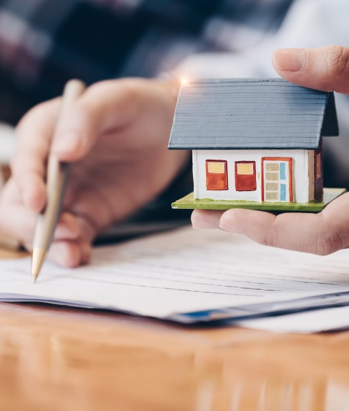 Hands with paperwork and small house model
